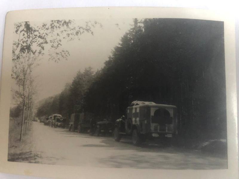 Une colonne d'ambulances roule sur une route bordée d'une forêt de sapins.