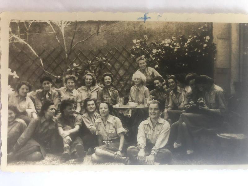 Photo de groupe d'une vingtaine de femmes assises et debout dans un jardin, autour d'une table.