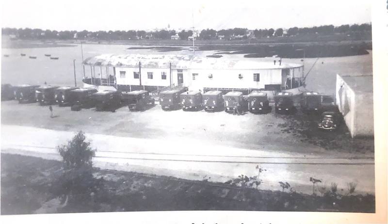 Vue d'ensemble d'une péniche blanche amarrée au bord du fleuve, avec une rangée d'ambulances garées devant.